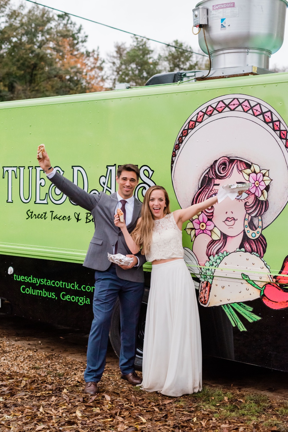 A couple celebrating with tacos in front of the Tuesdays truck